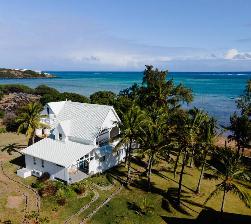 an aerial view of a white house with palm trees and the ocean at Bigarade sur Mer 