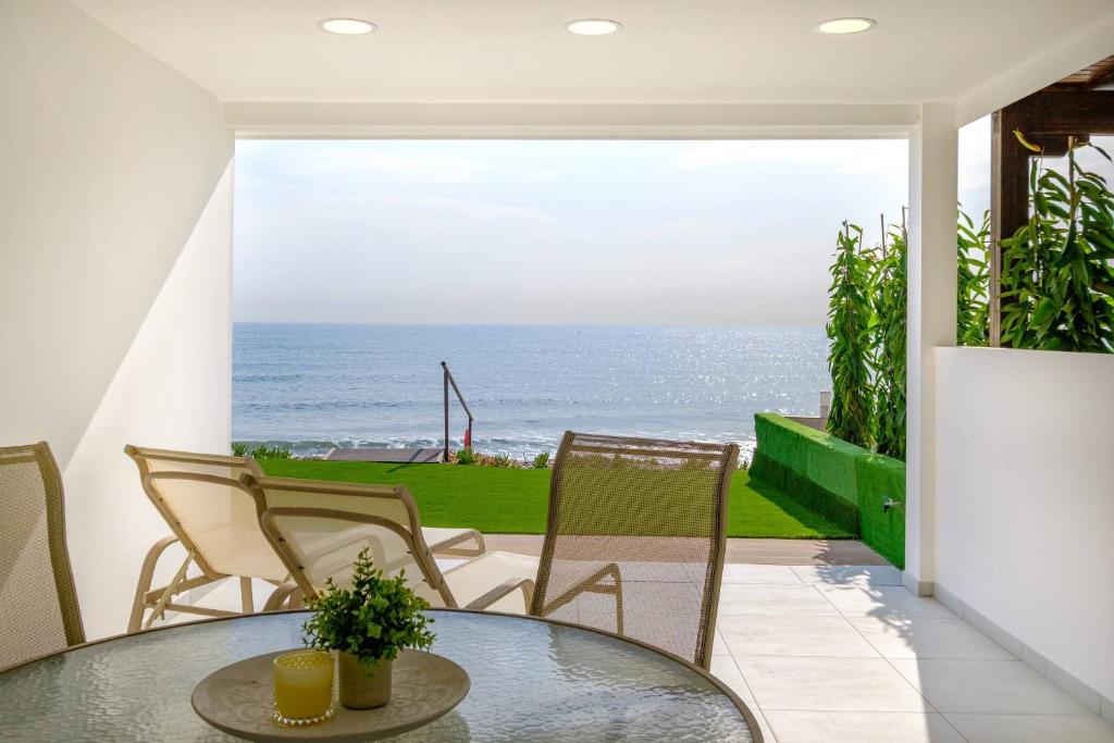 a patio with a table and chairs and the ocean at Wavestone Beachfront House in Meneou