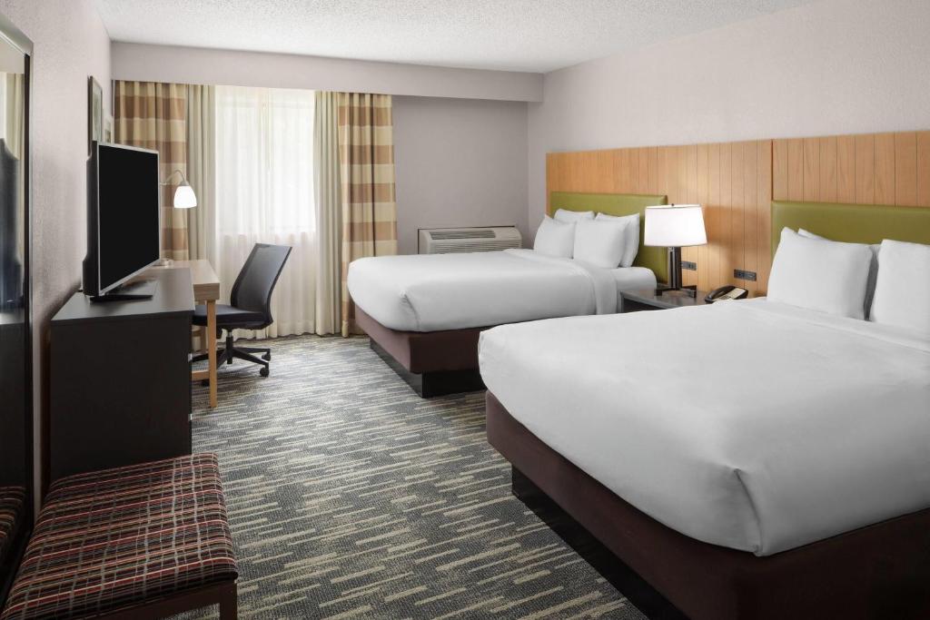 a hotel room with two beds and a flat screen tv at Wingate by Wyndham Lincoln Airport East I-80 in Lincoln