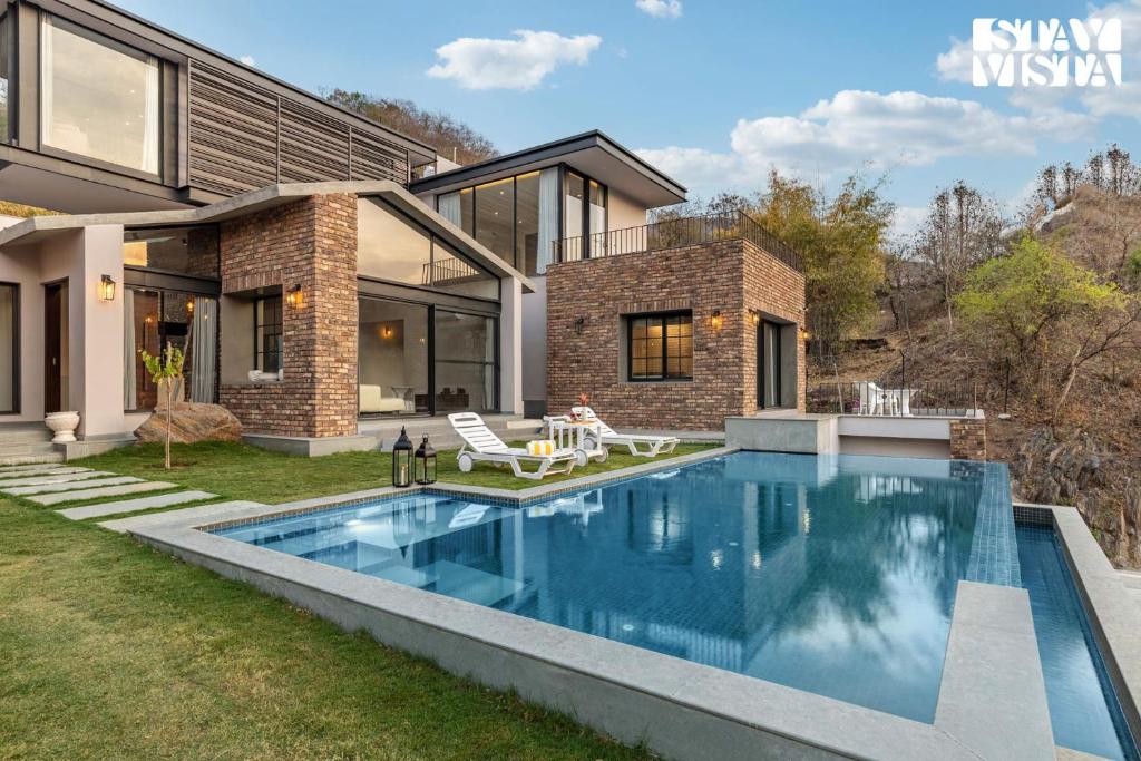 une piscine dans l'arrière-cour d'une maison dans l'établissement StayVista's Ikebana - Living By The Forest Edge - Mountain-view Villa with Infinity Pool, Lawn, & Indoor-Outdoor Games, à Udaipur