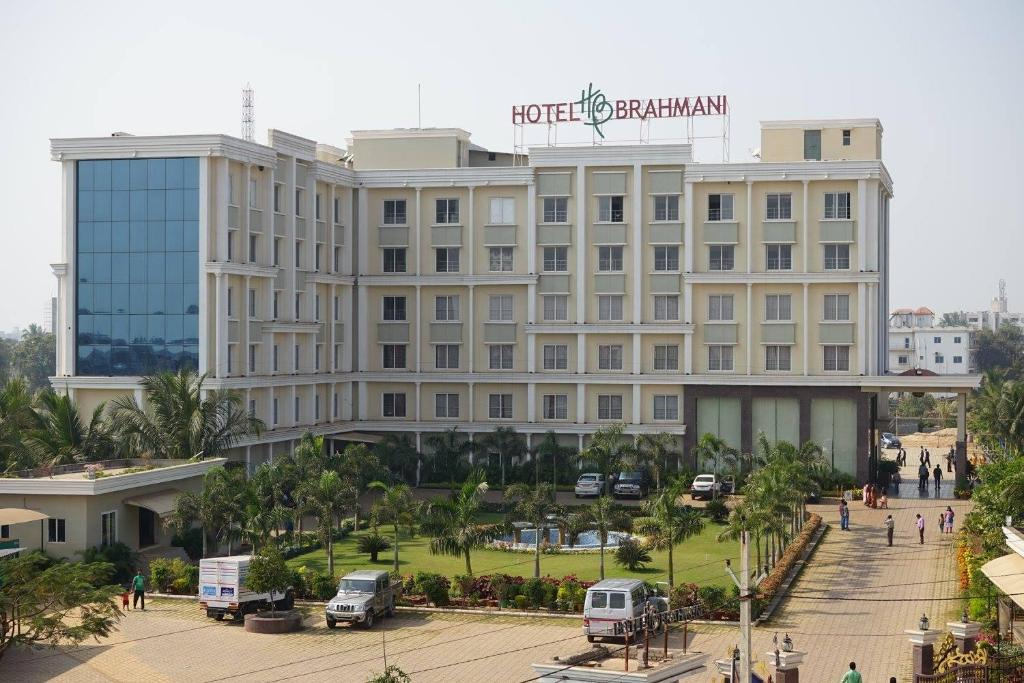 een hotelgebouw met auto's die ervoor geparkeerd staan bij Hotel Brahmani in Jajpur Road
