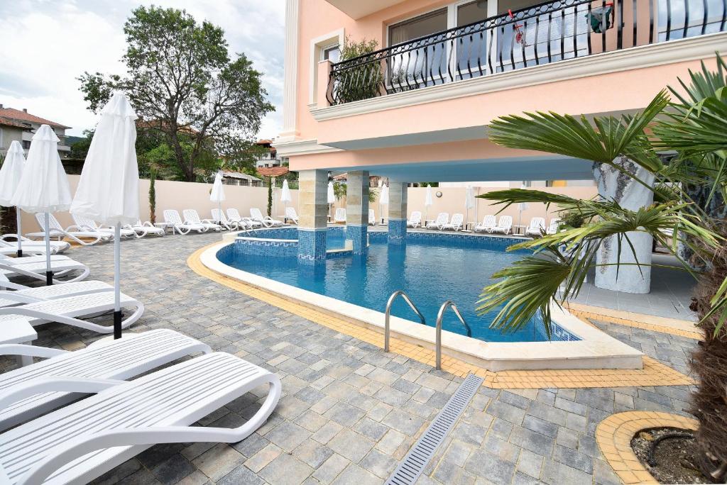 a hotel swimming pool with lounge chairs and umbrellas at Sirena Palace Family Hotel in Obzor