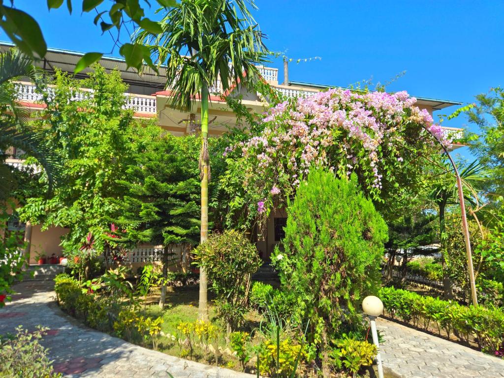 um jardim em frente a um edifício com flores cor-de-rosa em Hotel Tree Tops- A Serene Friendly Hotel in Sauraha em Chitwan