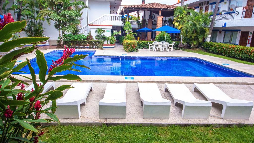 a swimming pool with white lounge chairs next to it at Hotel Hacienda Vallarta - Playa Las Glorias in Puerto Vallarta