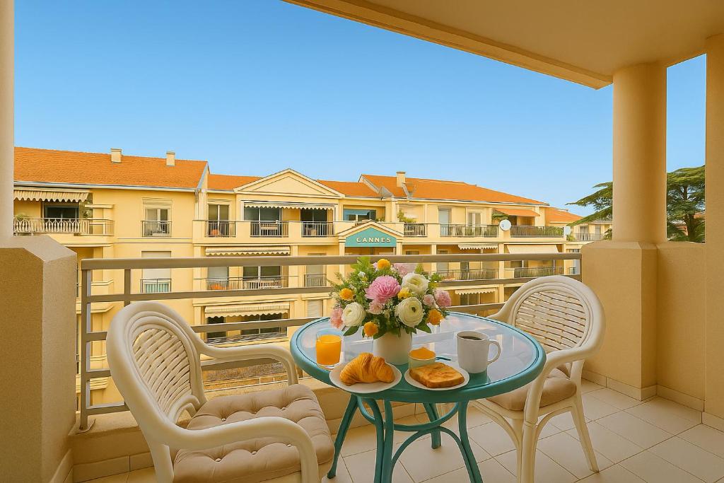 ein Tisch mit einer Vase mit Blumen auf einem Balkon in der Unterkunft FRGK "Gallieni Terrasse au calme" in Cannes