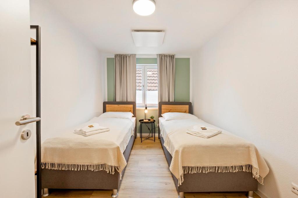 two beds in a small room with a window at CharmÖHR Homes in Öhringen