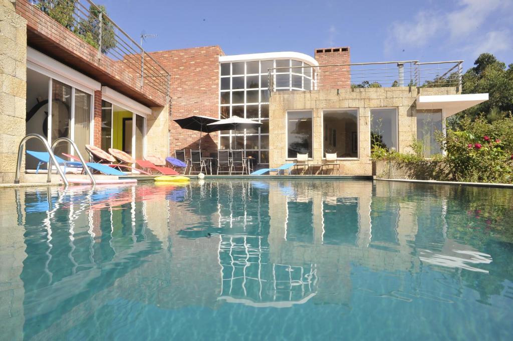 uma piscina com água azul em frente a um edifício em Casa Penedo da Saudade em Afife