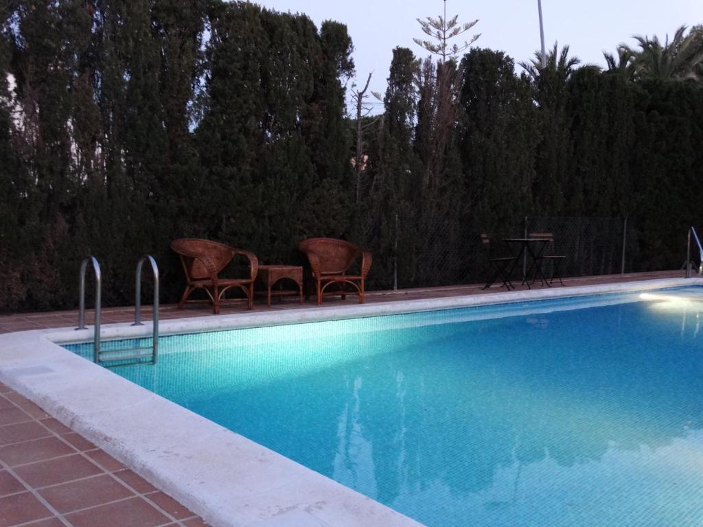 una piscina con 2 sillas y una mesa en La casa de Mary, en Torrevieja