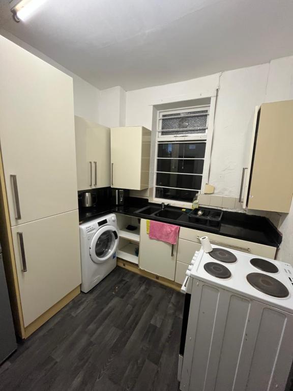 オールダムにあるCooperate home2の小さなキッチン(白いキャビネット、洗濯機、乾燥機付)