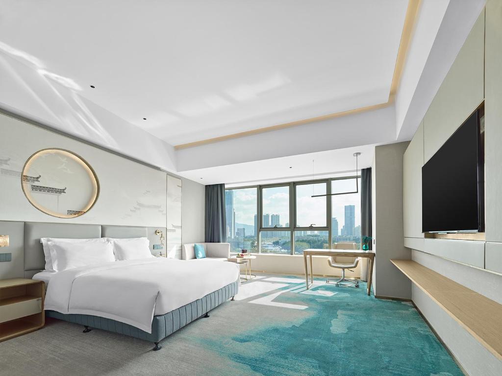 a bedroom with a bed and a flat screen tv at Shenzhen Grand Skylight Garden Hotel in Shenzhen