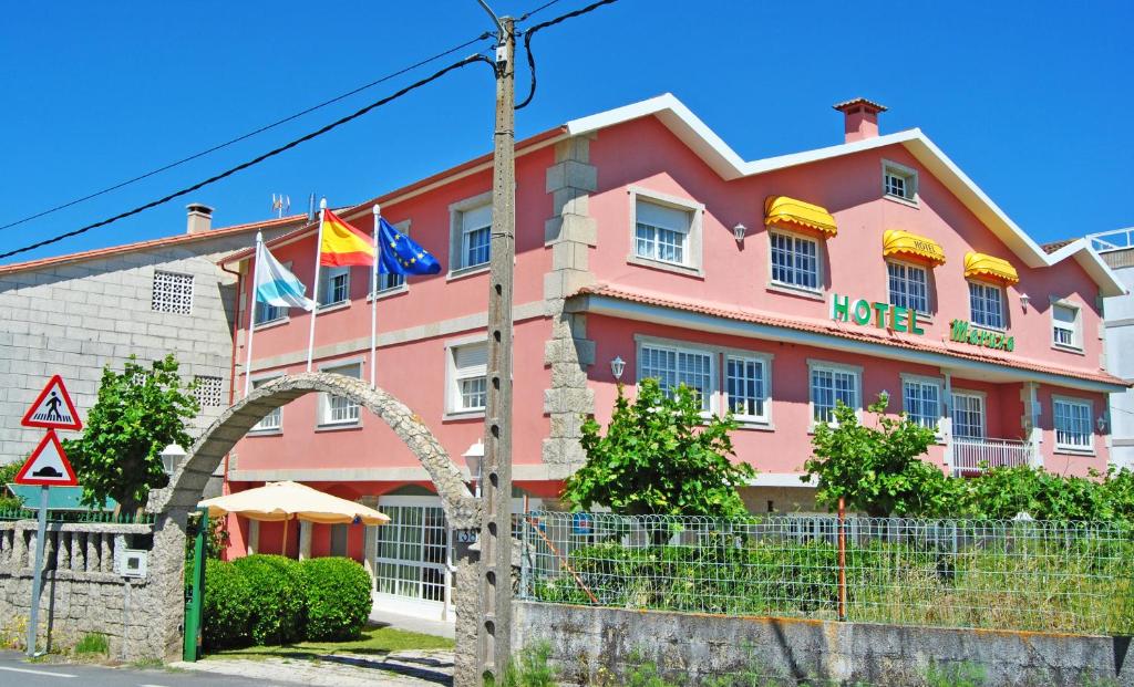 a pink building with flags in front of it at Hotel Maruxa in A Lanzada