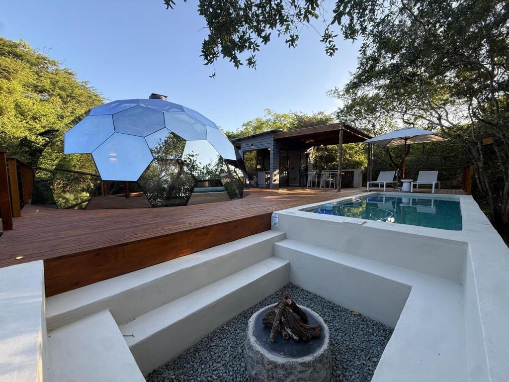 a house with a swimming pool and an umbrella at The Dome Luxury Safari Villa in Hluhluwe