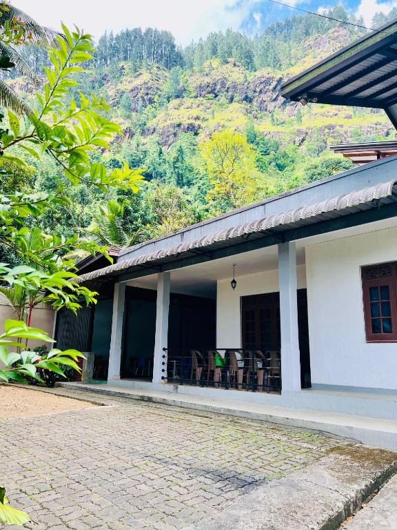 un bâtiment blanc avec des tables et des chaises devant une montagne dans l'établissement Lucky Holiday Bungalow, à Elkaduwa