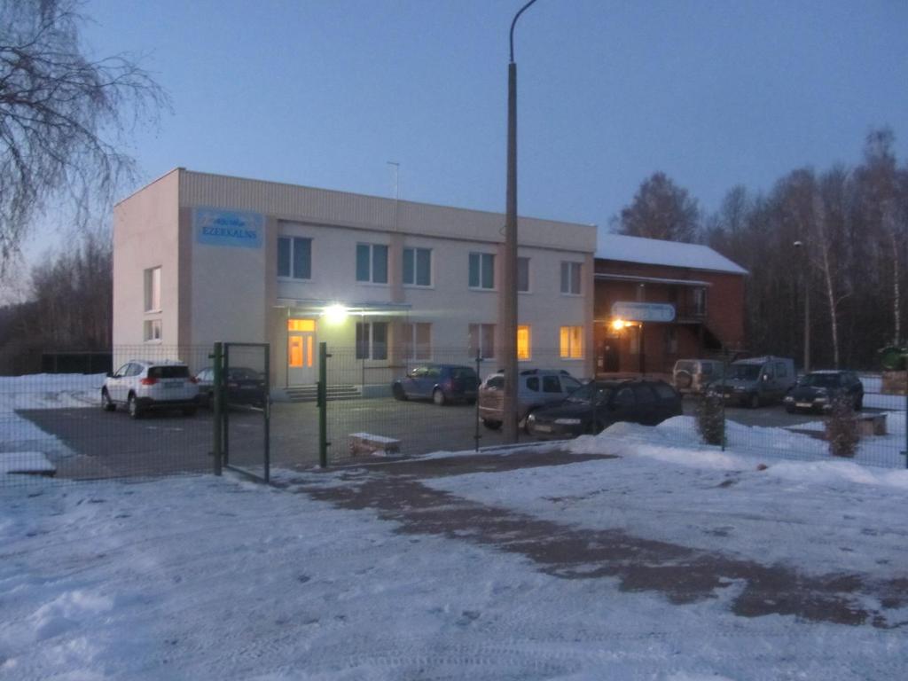 budynek z samochodami zaparkowanymi na parkingu w obiekcie Viesu māja Ezerkalns w mieście Krasław
