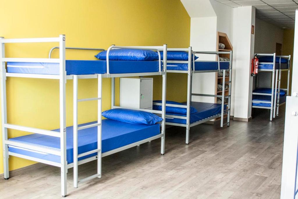 Cette chambre comprend 3 lits superposés avec des oreillers bleus. dans l'établissement De Camino, à Arzúa