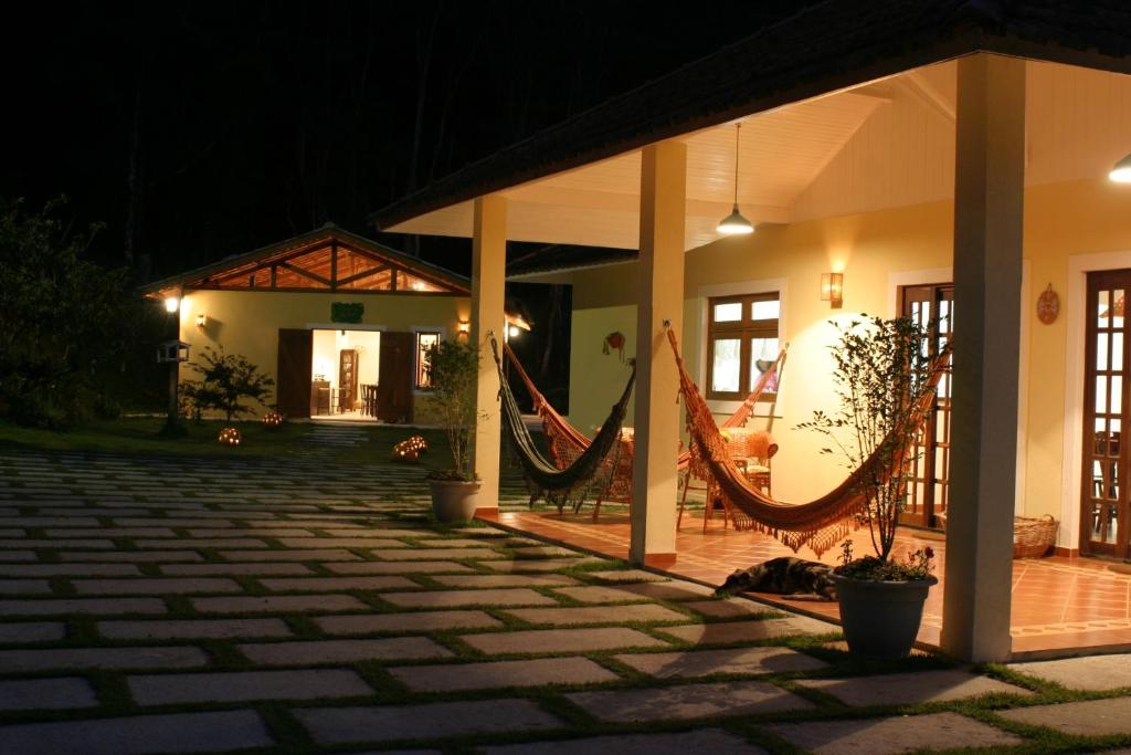 une maison avec des hamacs dans la cour la nuit dans l'établissement Pousada Vilarejo do Quim, à Tapiraí