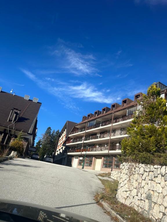 an apartment building with a stone wall next to a street at Atila Nature Home in Bjelašnica