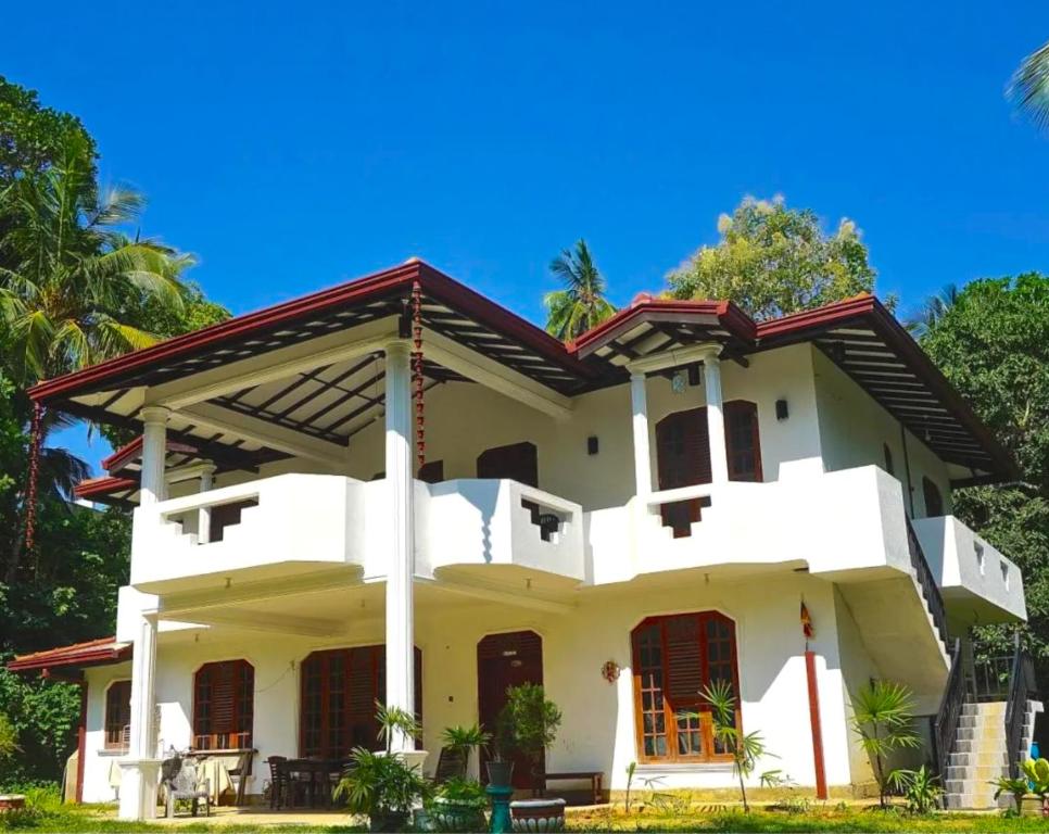 a white house with trees in the background at Barefoot Beach - Hiriketiya in Dickwella