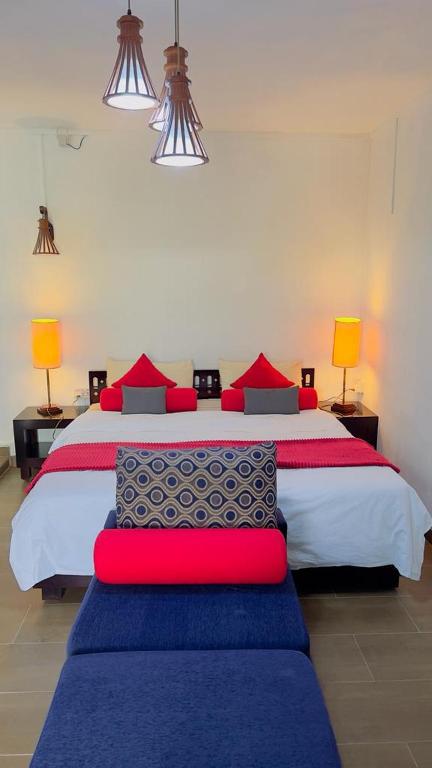 a bedroom with a large bed with red and blue pillows at Ahavah Guesthouse in Trou d'Eau Douce