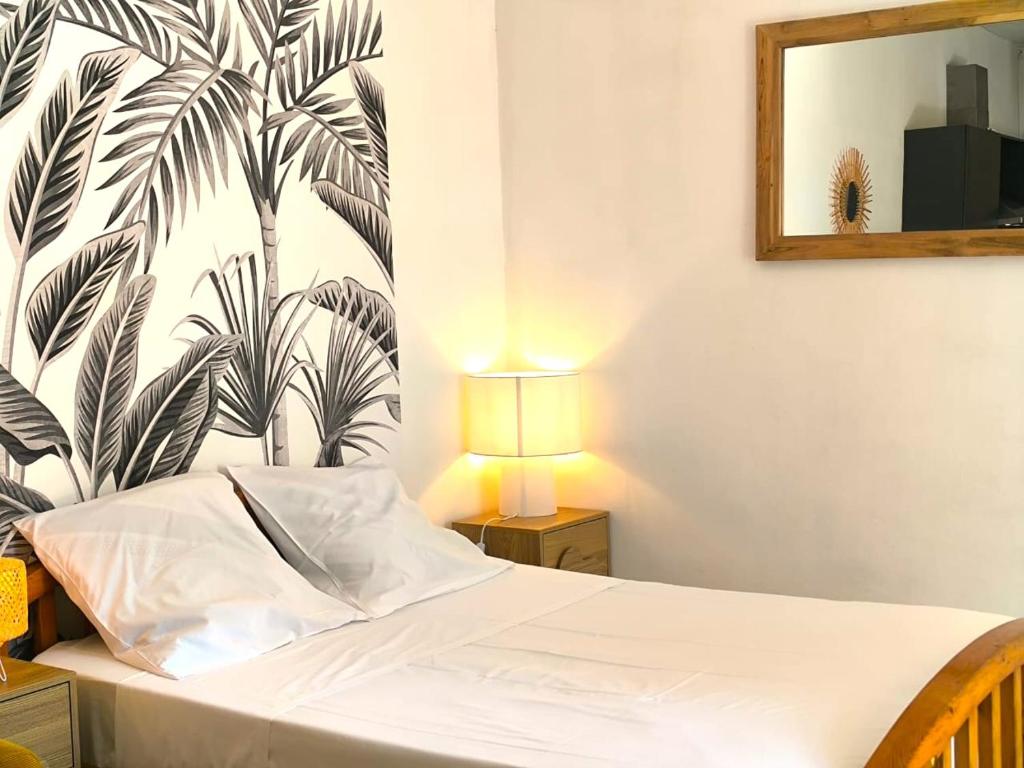 a bedroom with a white bed with a black and white wallpaper at Le Rodrigues - plages - parking - clim - wifi in Saint-Gilles les Bains