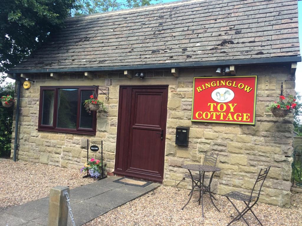 a tiny cottage with a red sign on it at Toy Cottage Sheffield in Sheffield