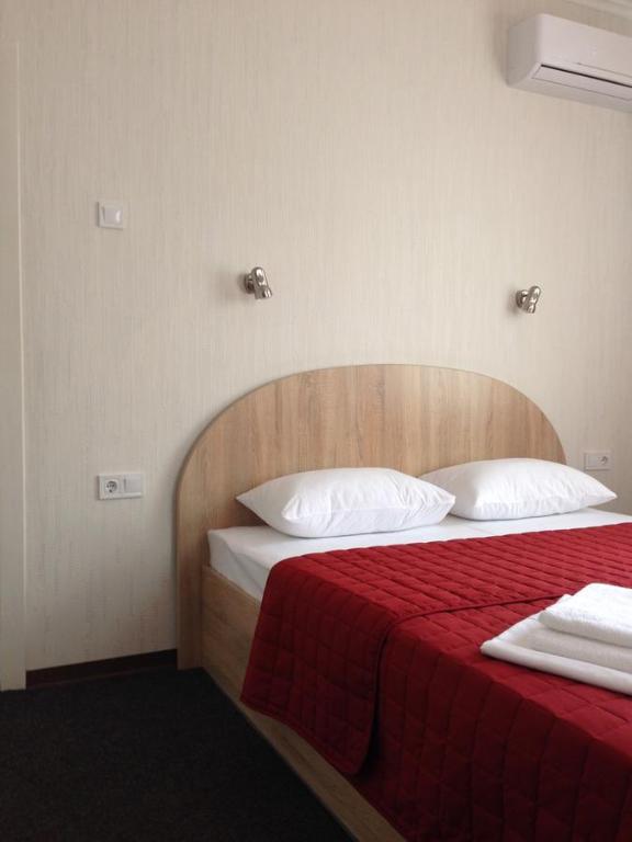 um quarto com uma cama com um cobertor vermelho e almofadas brancas em U Fedora em Oleksandriya