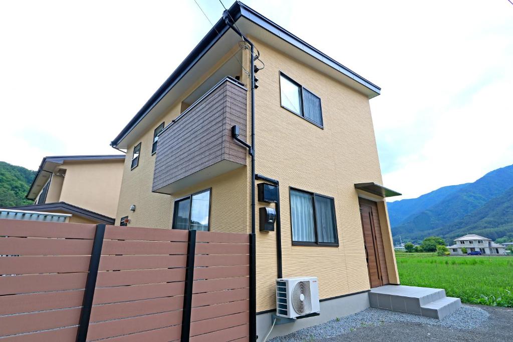 een huis met een hek ervoor bij コテージ鎌倉 in Fujikawaguchiko