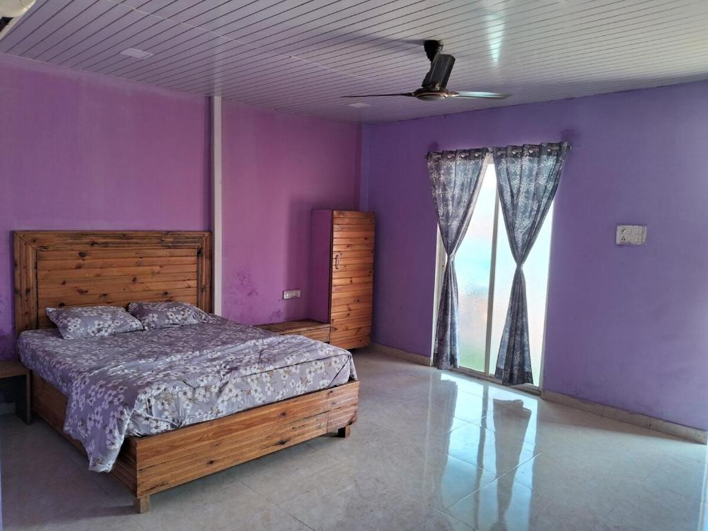 1 dormitorio con paredes moradas, 1 cama y ventana en Best and biggest place to have quality time, en Malavli