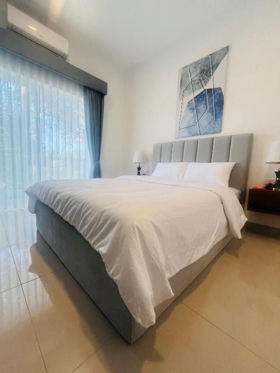 a bedroom with a large bed with white sheets at Casa Santorini Negombo Resort Apartment in Negombo