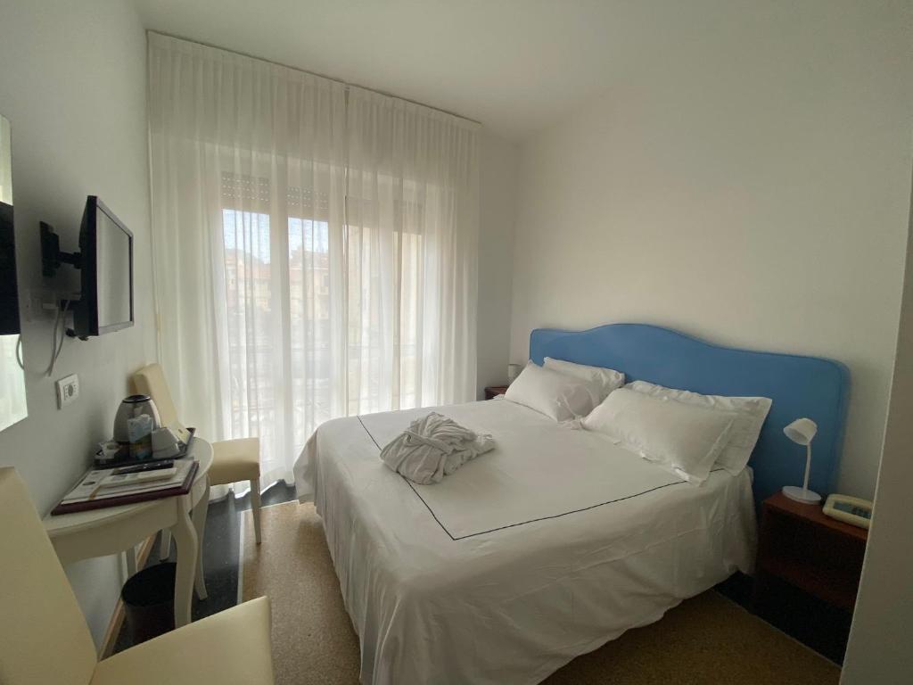Un dormitorio con una cama con cabecero azul y una ventana. en Sleep Al 25, en Finale Ligure