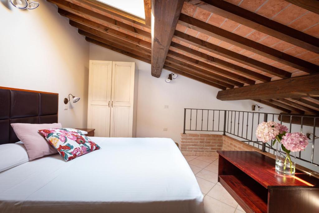 1 dormitorio con cama blanca y techo de madera en Hotiday Apartments Costa degli Etruschi, en Vada