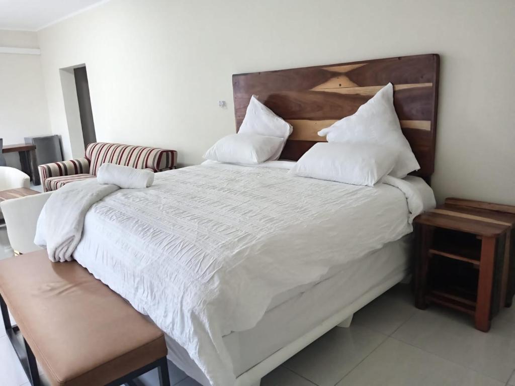 una habitación con una cama grande con sábanas y almohadas blancas en Wildlife Oasis, en Marloth Park