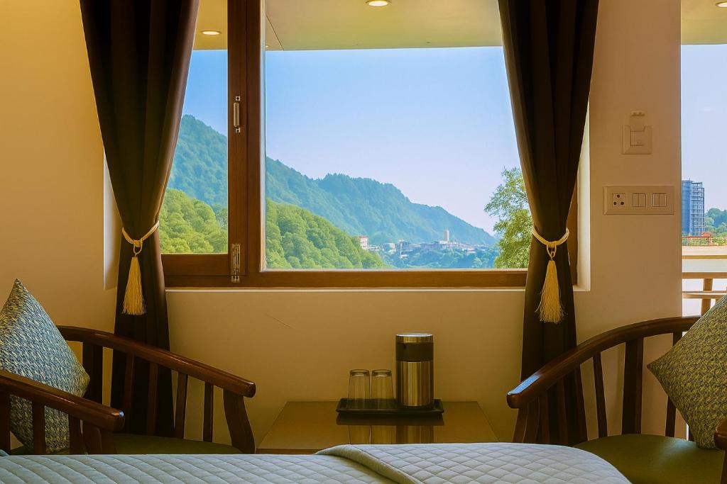 Un dormitorio con una ventana con vista a la montaña. en Hotel Sunny Cot - Free Mall Shuttle and Parking, en Mussoorie