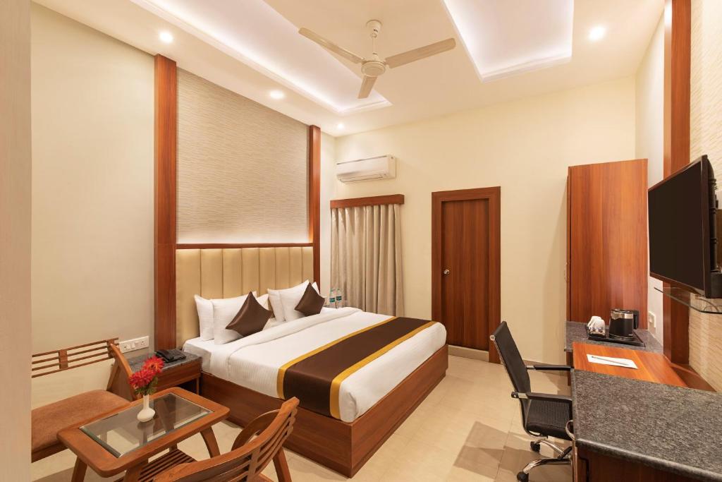 Una habitación de hotel con una cama, un escritorio y un televisor. en Clarks Collection Maanya, en Bareilly