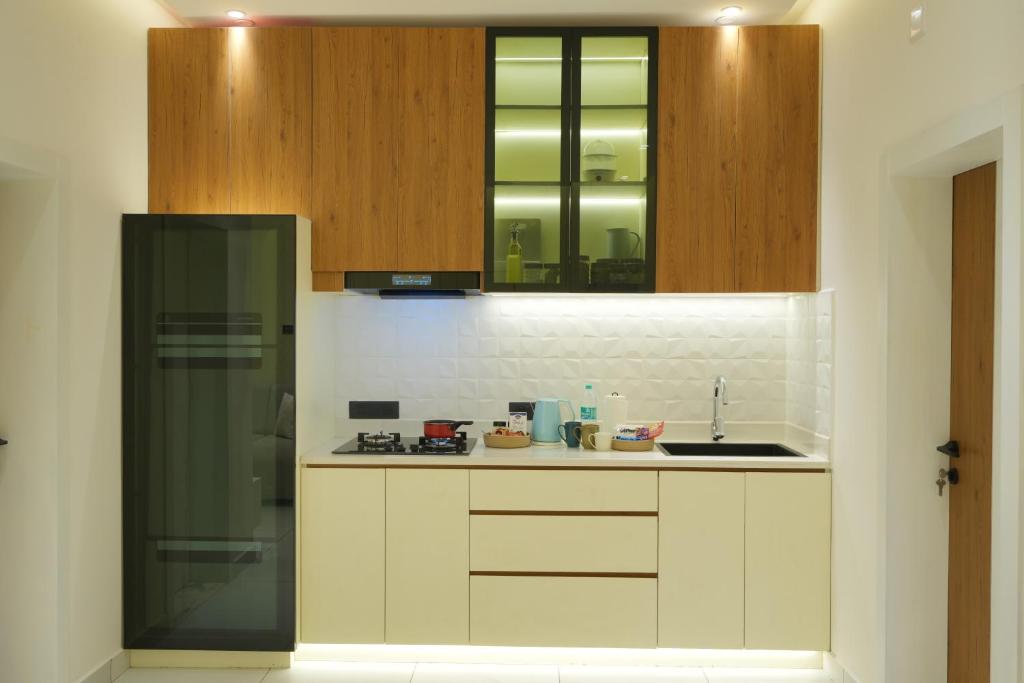 a kitchen with white counters and wooden cabinets and a sink at Royale Suites - 1 BHK Serviced Apartment in Kadayirippu