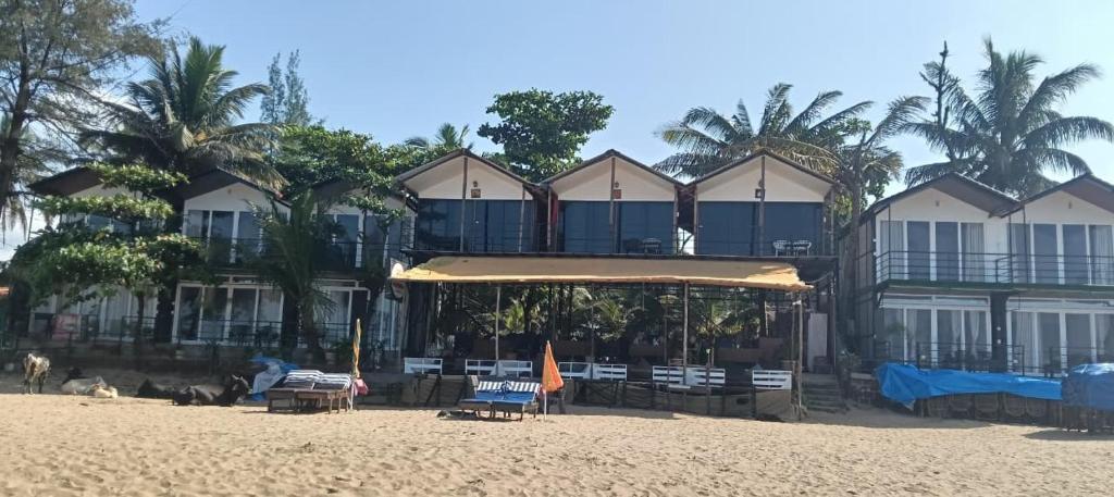 a building on the beach with chairs and umbrellas at Casa Beach hut Resort in Palolem