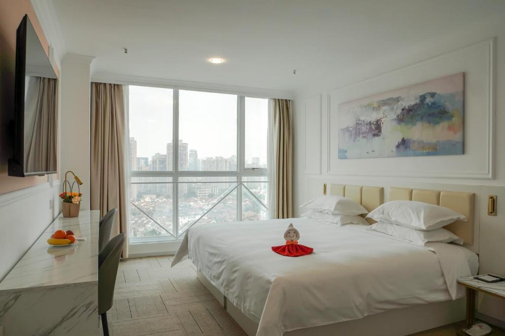 a bedroom with a white bed with a large window at Magnificent International Hotel in Shanghai