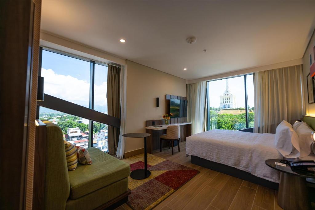 a hotel room with a bed and a desk and a window at Hotel Hampton By Hilton Santiago De Los Caballeros in Santiago de los Caballeros