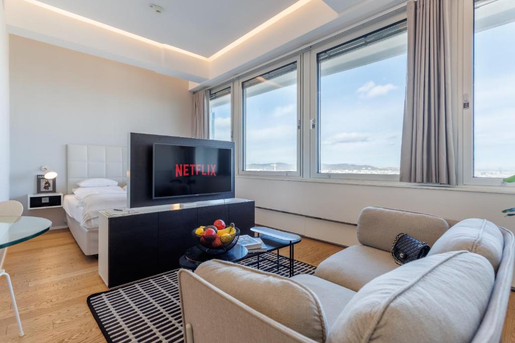 a living room with a couch and a tv at Skyline View Vienna - Gym - Parken - Supermarkt - Restaurant - Self Check in in Vienna
