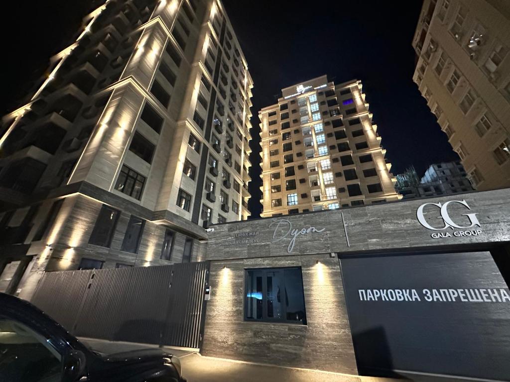 a building with a sign in front of some tall buildings at Duet in Bishkek