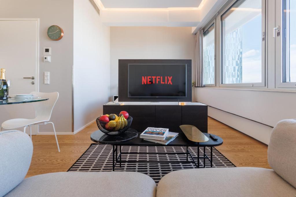 a living room with a television and a bowl of fruit on a table at Skyline View - Gym - Parking - Supermarket - Restaurant - Self Ceck In in Vienna