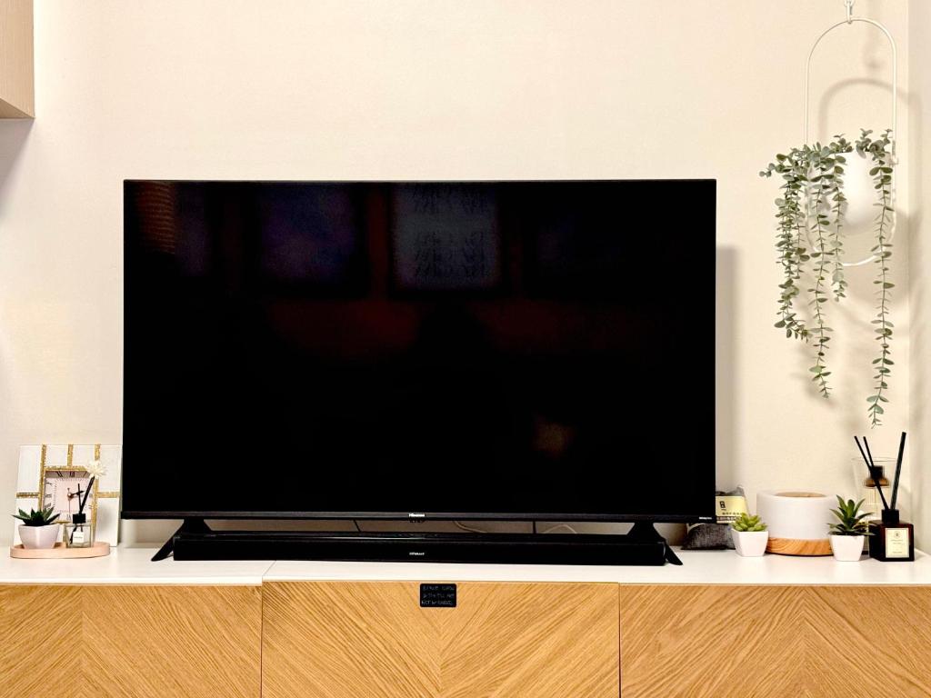 a large flat screen tv sitting on top of a cabinet at Suite Escapes Brenthill Baguio 1 Bedroom in Baguio