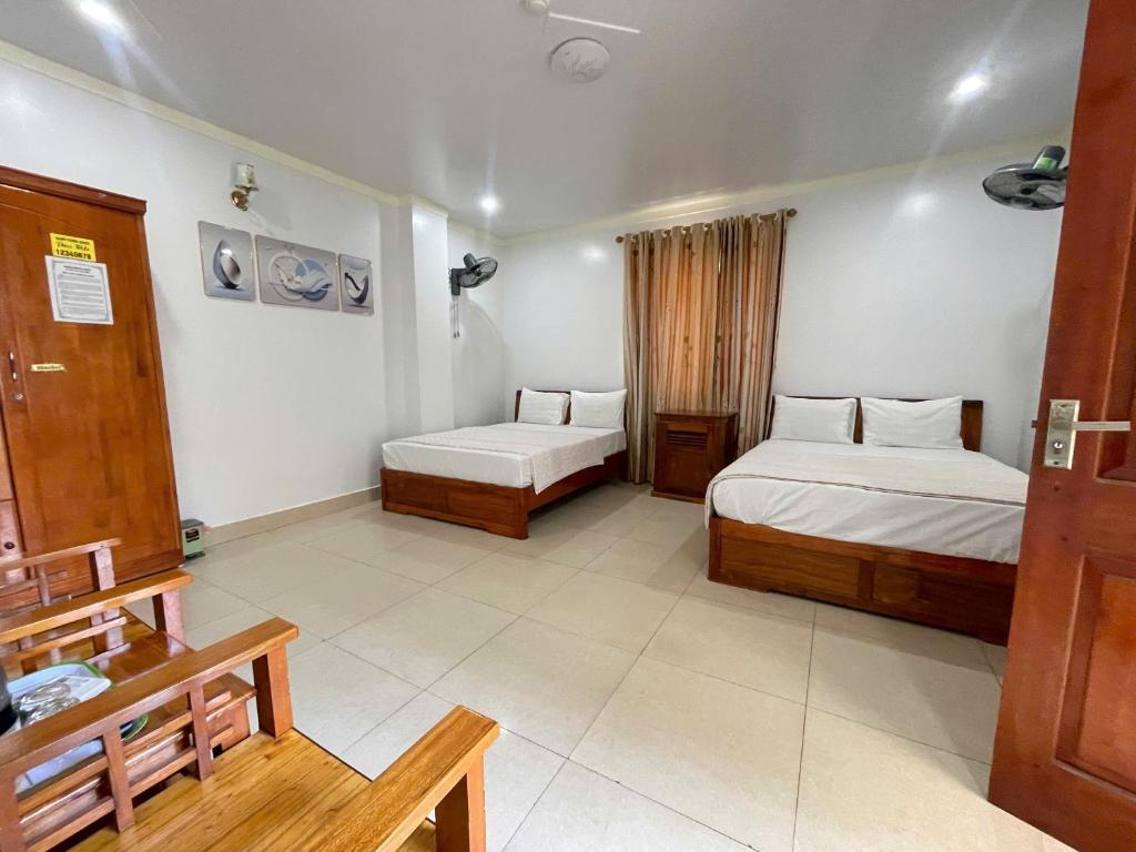 a hotel room with two beds and a table at Manh Vuong Hotel &Travel in Cat Ba