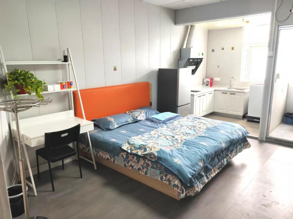 a bedroom with a bed and a desk and a kitchen at Suhe Homestay in Nanjing