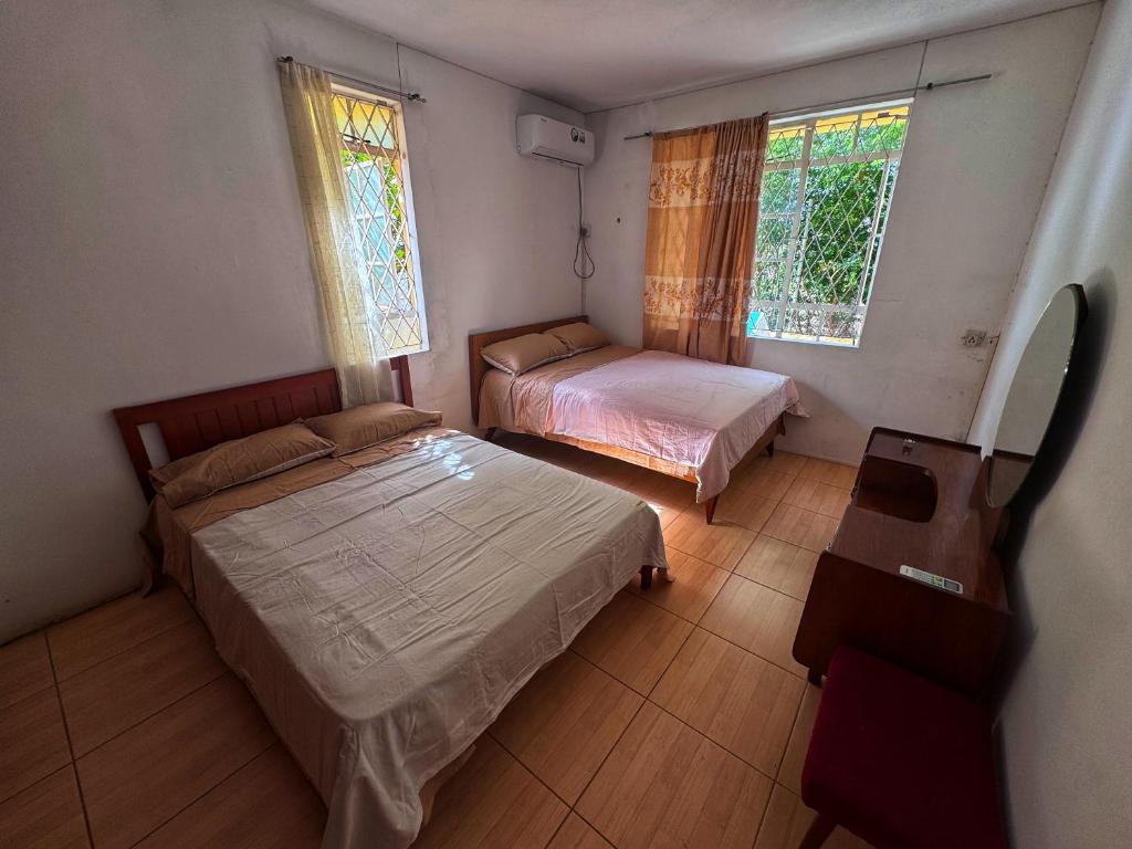 a bedroom with two beds and a table and two windows at 毛里求斯民宿 in Roche Bois