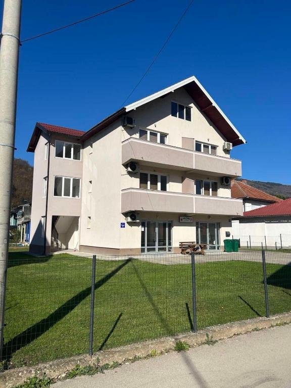 a white building with a fence in front of it at Sobe Holiday Goražde in Goražde