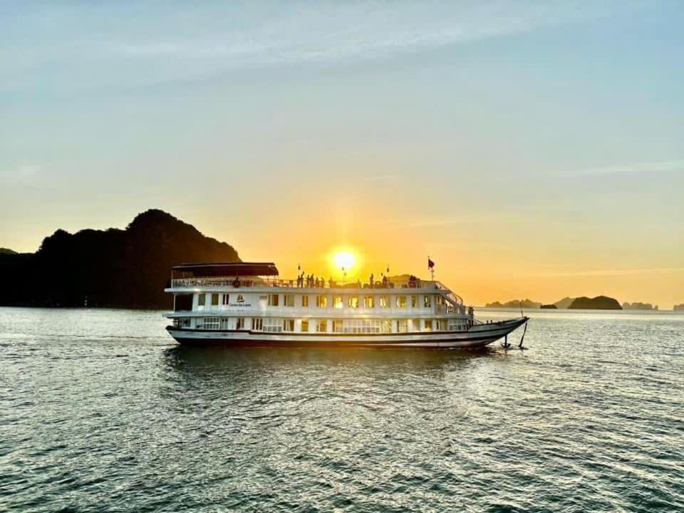 een boot op het water met de zonsondergang op de achtergrond bij Garden Legend 2 cruise in Ha Long