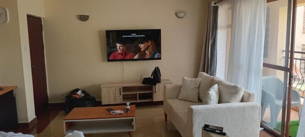 een woonkamer met een bank en een tv aan de muur bij makao apartment in Nairobi