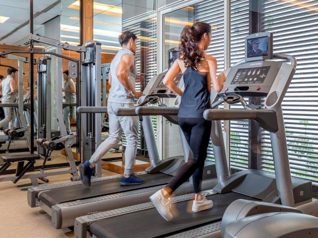 een man en een vrouw op een loopband in een sportschool bij Pullman Bangkok King Power in Bangkok