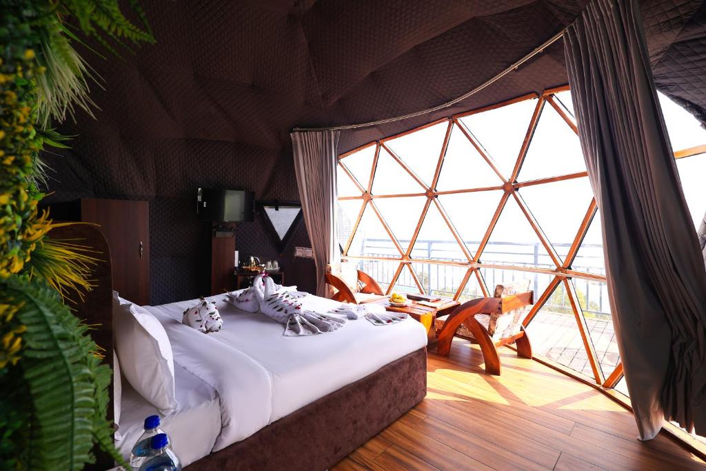 a bedroom with a bed and a large window at ECKO Kasang Regency Hill Resort in Lansdowne